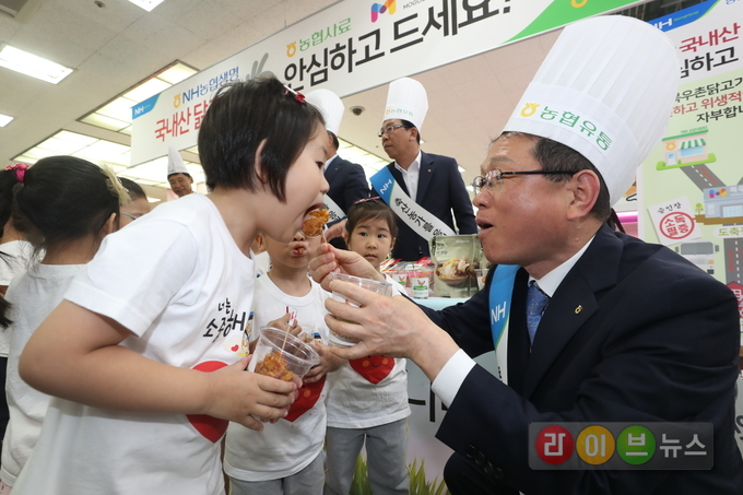 19일 서울 서초구 농협하나로마트 양재점에서 AI로 어려움을 겪고 있는 양계 농가도 돕고 소비자 생활물가에도 기여코자 NH농협생명, 농협사료, 농협목우촌의 후원으로 실시한 닭고기 상생마케팅 후원금 전달식에서 김원석 농협경제지주 농업경제대표이사(사진 오른쪽)가 아이들에게 치킨을 나누어주고 있다.