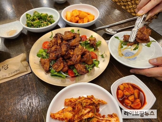 식탁 가운데 놓인 음식을 집게를 이용해 개인 앞접시에 옮기고 있다.