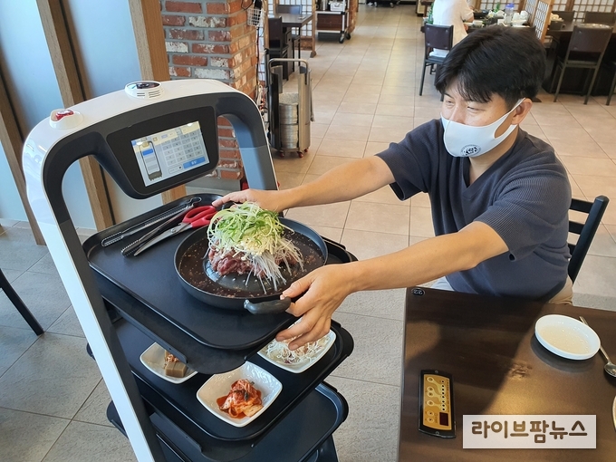 한우프라자의 고객이 서빙로봇을 통해 주문한 음식을 받고 있다.