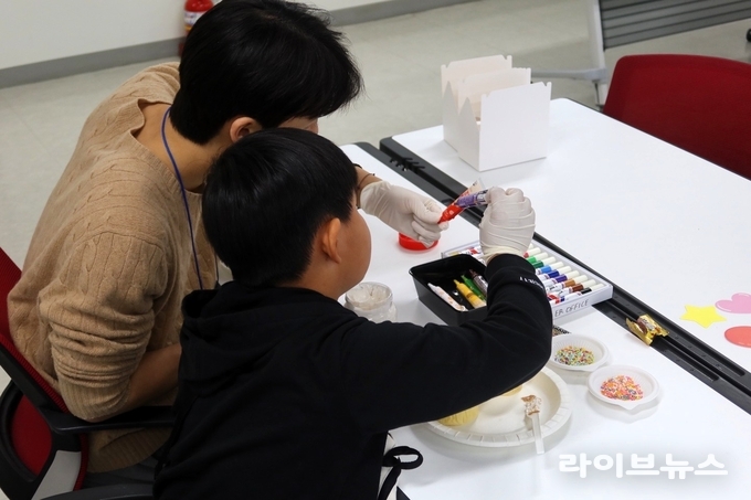 유타대학교 아시아캠퍼스 멘토링 프로그램에 참여한 아동이 대학생 멘토와 함께 컵케이크 만들기 활동을 체험하고 있다.(사진=유타대학교아시아캠퍼스)