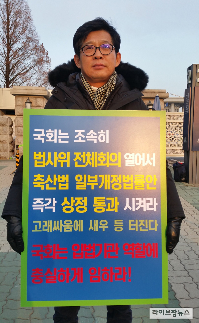 오리협회 김만섭회장이 영하 5도로 떨어진 14일 오전 여의도 국회의사당 앞에서 "축산법 일부개정법률안을 즉각 상정하라"는 1인 피켓시위를 벌이고 있다.  